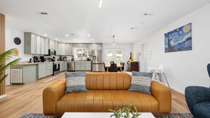 Una sala de estar moderna con un sofá de cuero, una mesa de comedor y una cocina al fondo.