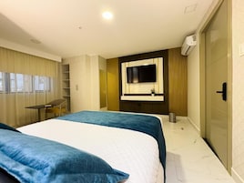 Una habitación de hotel moderna con dos camas, un espejo grande, un televisor y un armario.
