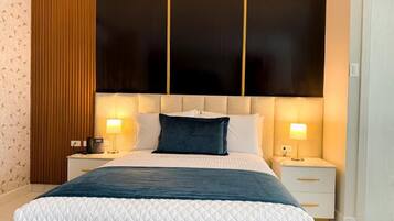 A modern bedroom with a large bed, two bedside tables, and a wall panel design.