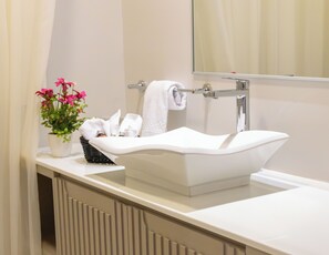 A bathroom with a white sink, a mirror, and a potted plant with pink flowers. - Hotel DSH (Manta)