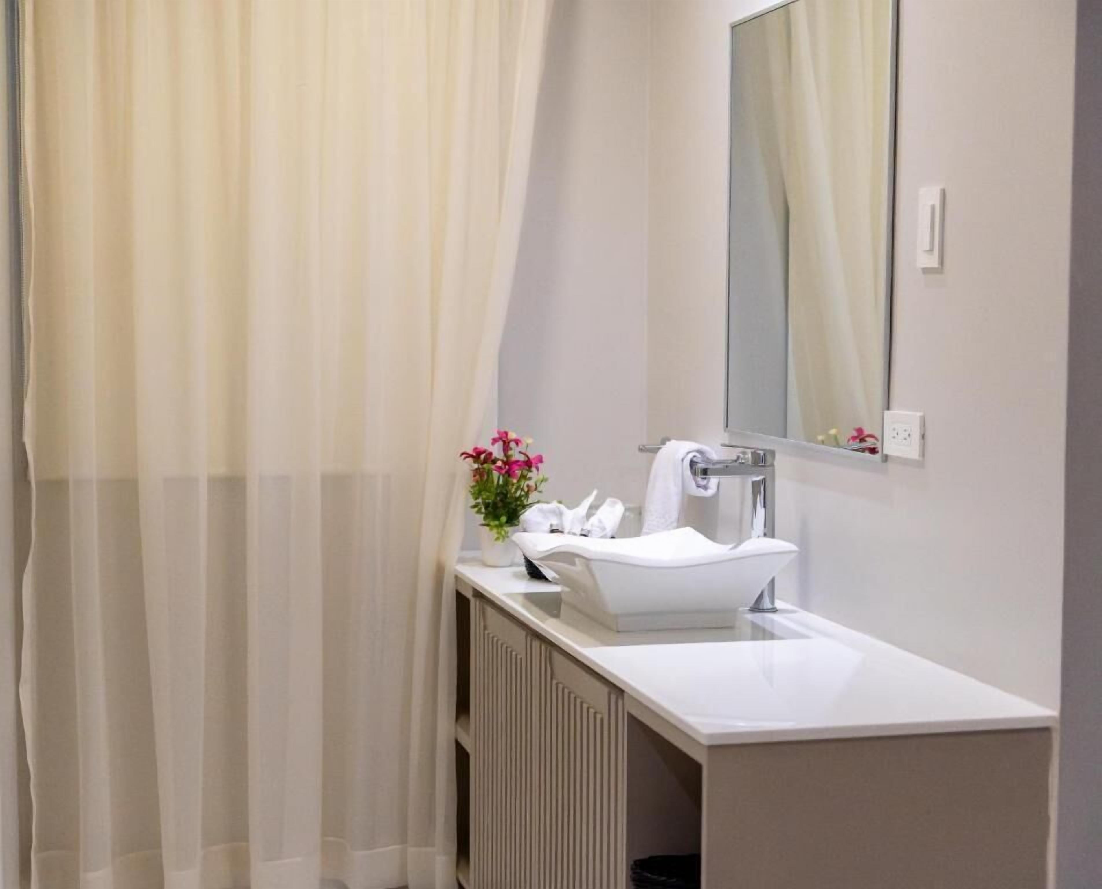 Un baño moderno con un lavamanos blanco, un espejo y un radiador.