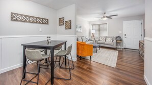 A modern living room with a dining area, featuring a wooden floor, a sofa set, a coffee table, and a ceiling fan. - Modern & Inviting Remodeled 3BR in Independence, KS! (Independence)