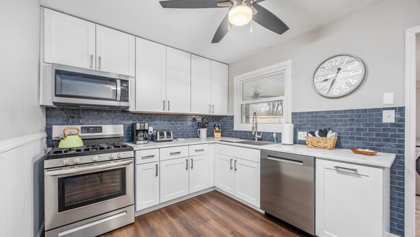 A modern kitchen with white cabinets, stainless steel appliances, a microwave, stove, and dishwasher. - Modern & Inviting Remodeled 3BR in Independence, KS! (Independence)