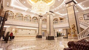 A spacious lobby with a grand chandelier, a staircase with golden statues, and a reception desk. - Vienna International Hotel Changsha Gaoqiao Branch (Changsha)