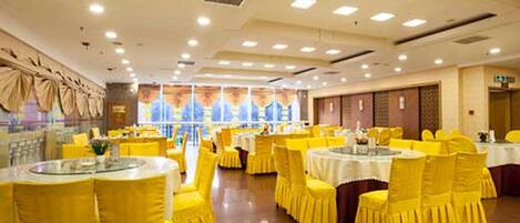 A banquet hall with round tables, yellow chairs, and a polished floor.