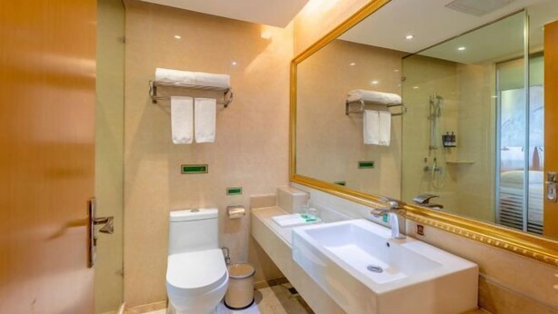 A modern bathroom with a toilet, bidet, and a large sink with a mirror. - Vienna International Hotel Changsha Gaoqiao Branch (Changsha)