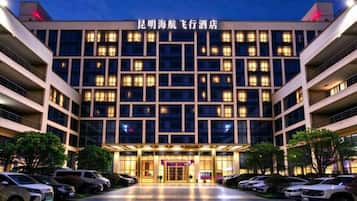 A multi-story hotel building with a prominent entrance and several parked cars in front.