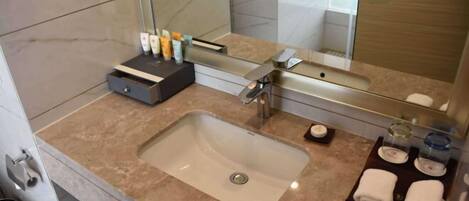 A modern bathroom with a large sink, mirror, and toiletries.