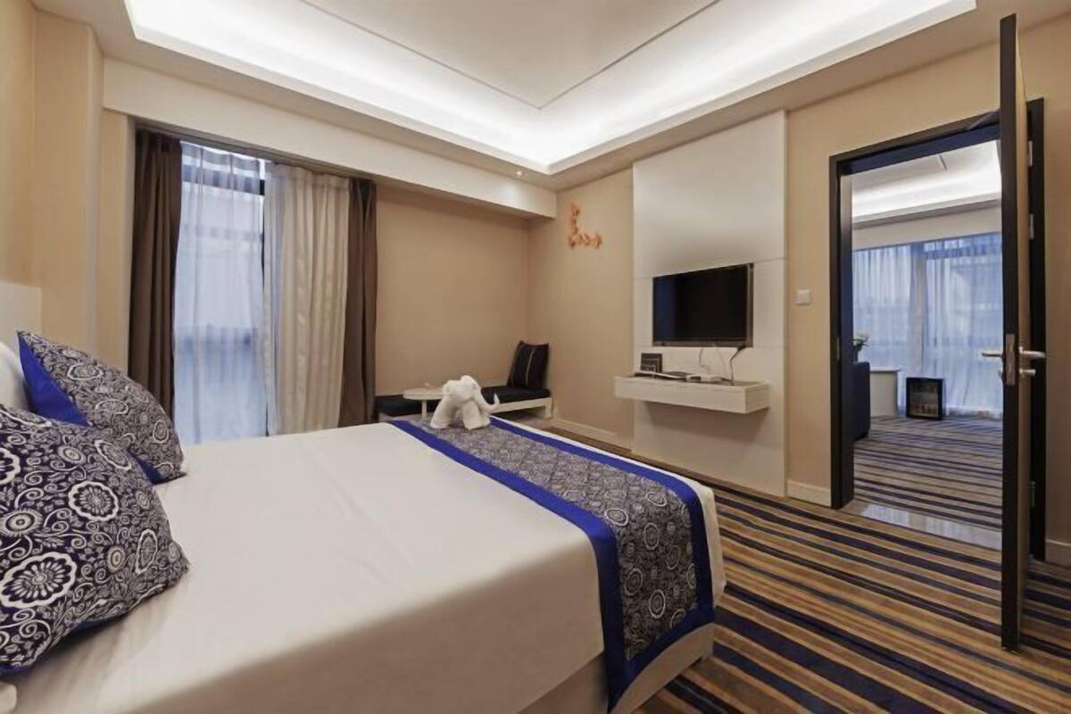 Una habitación de hotel con cama, escritorio, televisión y espejo.