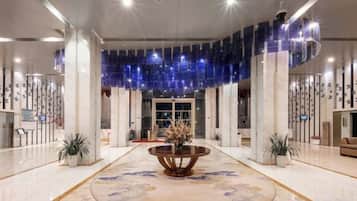 A spacious lobby with a central round table, a decorative ceiling, and a reception desk.