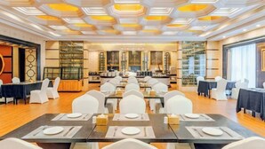 A spacious dining area with multiple tables and chairs, a modern ceiling design, and a view of the kitchen in the background. - CQ Second Normal University Academic Exchange Center Hotel (Chongqing)