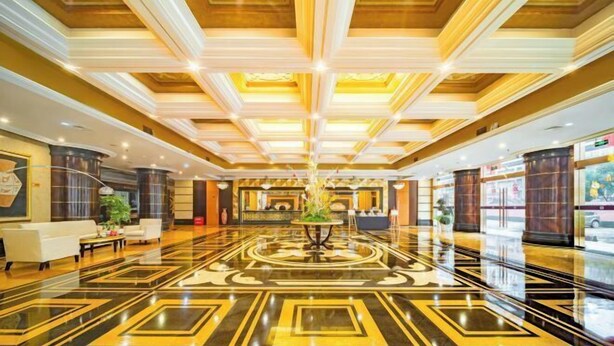 A spacious lobby with a polished marble floor, a central floral arrangement, and a reception desk. - CQ Second Normal University Academic Exchange Center Hotel (Chongqing)