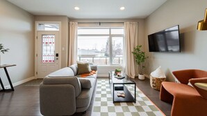 Un salon moderne avec un canapé, une table basse et un téléviseur fixé au mur.