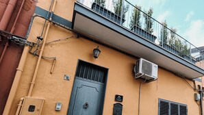 A building with a black door, a small mailbox, and an air conditioning unit. - Super-accessorised house suitable for families (San Gregorio di Catania)