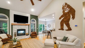 A spacious living room with a fireplace, a large flat-screen TV, and a stone accent wall. - 3800 sq ft of Fun! Sleeps 14 • Hot Tub • Pool Table • PAC-Man • Foosball  (McGaheysville)