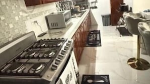 Een moderne keuken met houten kastjes, een gasfornuis en een betegelde spatwand.