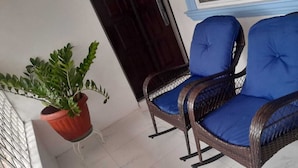 Two wicker rocking chairs with blue cushions on a balcony. - Cozy 2-bedroom stay with fireplace, AC, Wi-Fi and Comfort (Spanish Town)