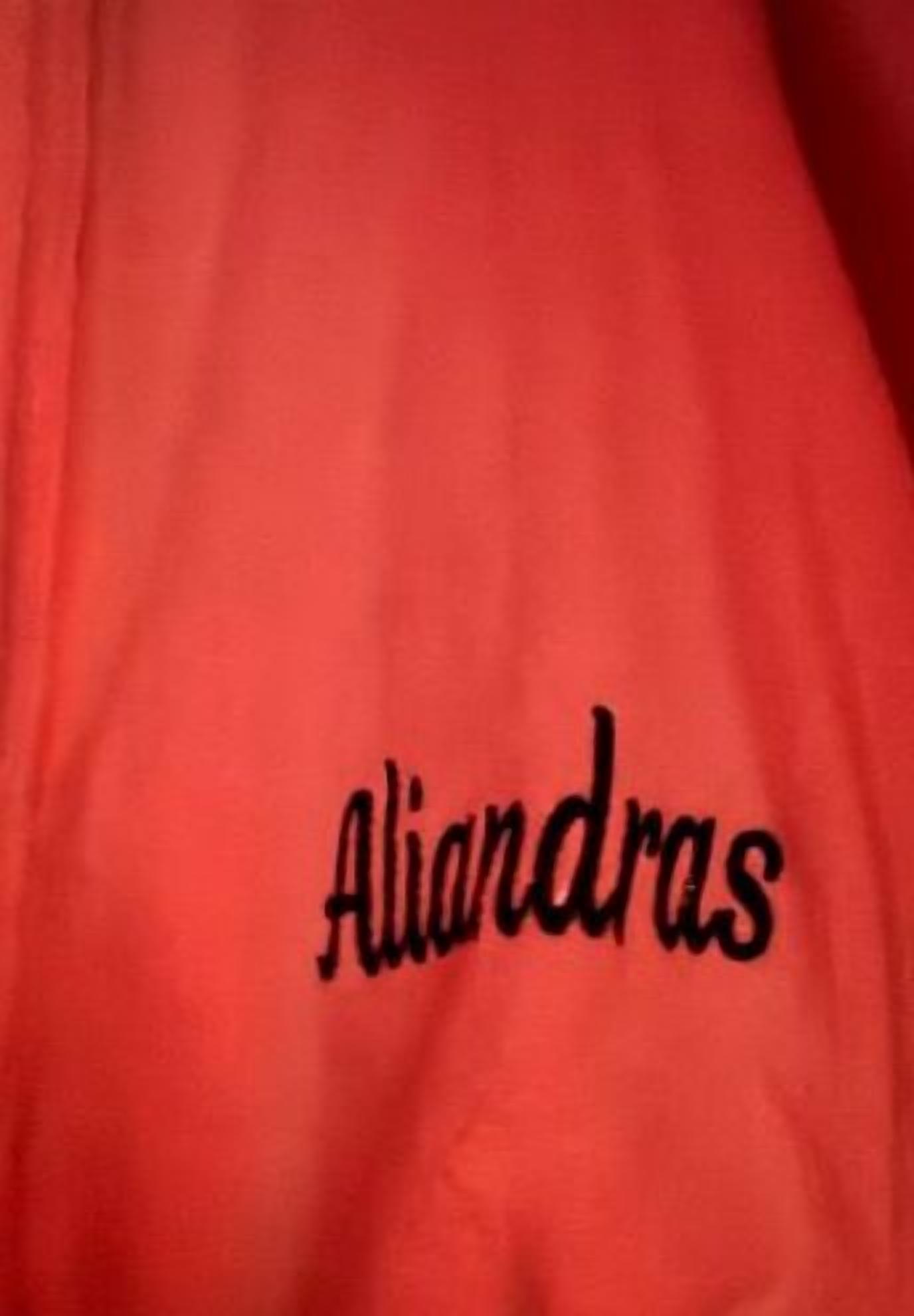 Tela vermella amb la paraula "Aliandras" brodada en negre.