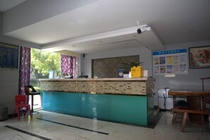 Un área de recepción con mostrador, una silla, una mesa y un tablón de anuncios.