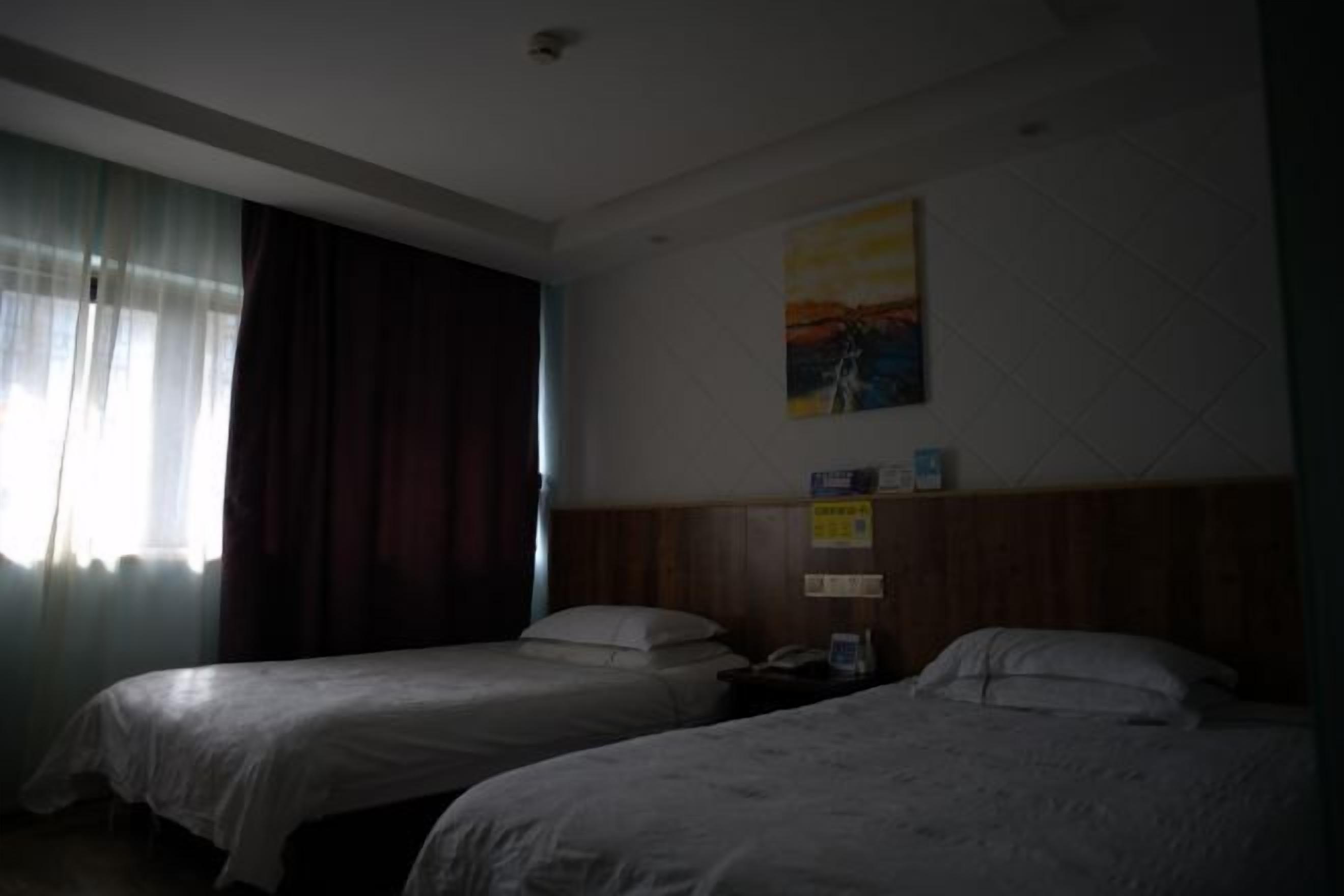 Een hotelkamer met twee bedden, een schilderij aan de muur en een raam met gordijnen.
