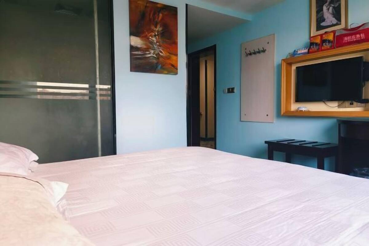A hotel room with a bed, a TV, and a painting on the wall.