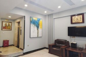 Una sala de estar moderna con un televisor de pantalla plana, un reloj y un cuadro en la pared.