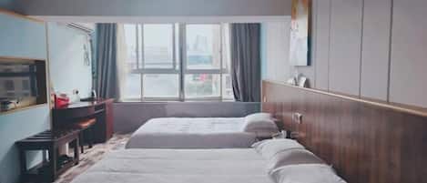 A hotel room with two beds, a desk, a chair, a wardrobe, and a large window with curtains.