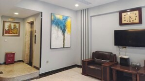 Un salon moderne avec un canapé en cuir marron, un téléviseur à écran plat et une horloge murale.