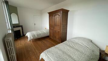 Een slaapkamer met twee eenpersoonsbedden, een houten garderobe, een radiator en een witte deur.