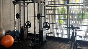 A gym with a squat rack, weight plates, and exercise balls. - Parque el Virrey modern & luxury apartment (Bogotá)