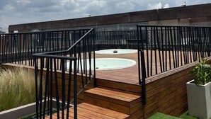 A rooftop deck with a wooden staircase, a pool, and a view of the cityscape. - Parque el Virrey modern & luxury apartment (Bogotá)