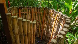 Une structure circulaire en bambou, dotée d’une ouverture centrale et entourée d’une végétation tropicale luxuriante.
