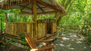 Une construction en bois, surmontée d’un toit de chaume, entourée d’une végétation luxuriante.