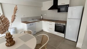 Une cuisine moderne avec des meubles blancs, une hotte noire, un four encastré et un réfrigérateur blanc.