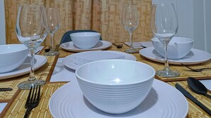 A dining table set with white plates, bowls, and wine glasses, with a patterned curtain in the background. - Charming 2-bedroom apartment with WiFi, AC in lovely Guadalajara de Buga (Guadalajara de Buga)