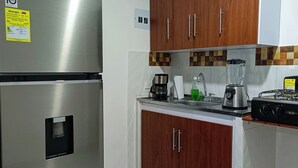 A modern kitchen with stainless steel appliances, wooden cabinets, and a tiled backsplash. - Charming 2-bedroom apartment with WiFi, AC in lovely Guadalajara de Buga (Guadalajara de Buga)