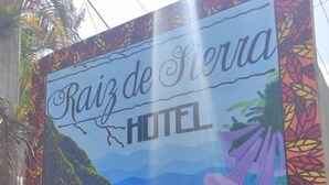 Μια πολύχρωμη πινακίδα για το ξενοδοχείο Raiz de Sierra, με σχέδιο που απεικονίζει ένα τροπικό τοπίο.