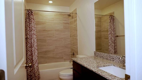 Une salle de bain avec douche, toilettes et lavabo.