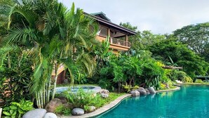 Una piscina rodeada de vegetación tropical y un edificio con balcón.