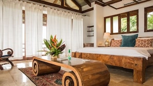 Un dormitorio con cama de madera, una mesita de centro de madera, una planta en maceta y un tapete estampado.