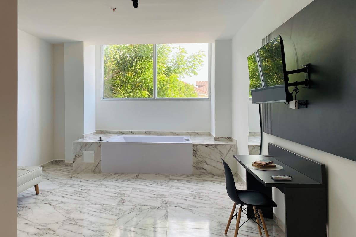 Un baño moderno con un ventanal amplio, una bañera y un tocador con espejo.