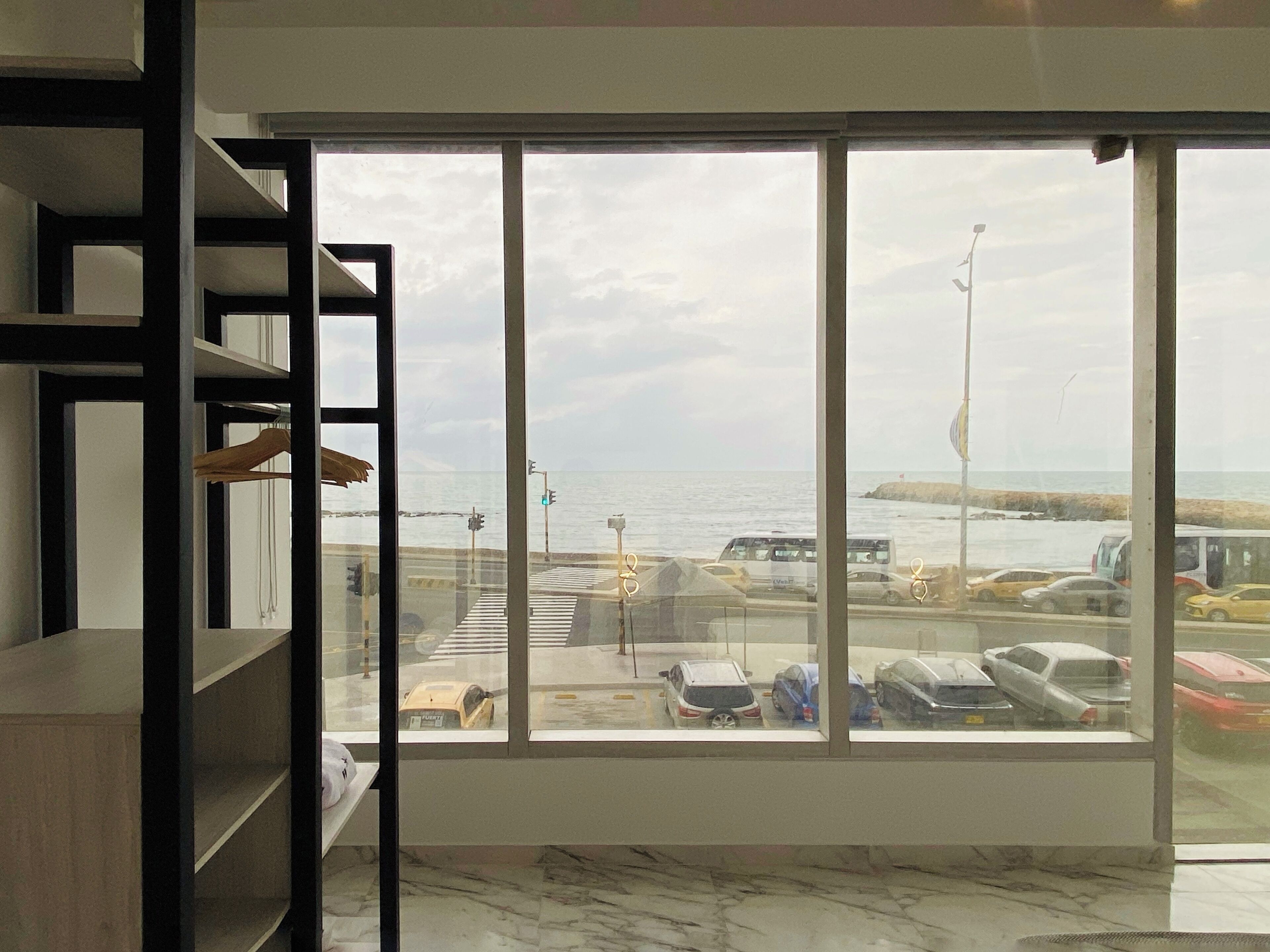 Habitación con un amplio ventanal que da a un estacionamiento y al mar.