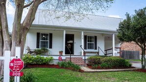 A white two-story house with a front porch, a stop sign, and a mailbox. - Charming 2-bedroom house in fabulous Breaux Bridge with WiFi, AC (Breaux Bridge)