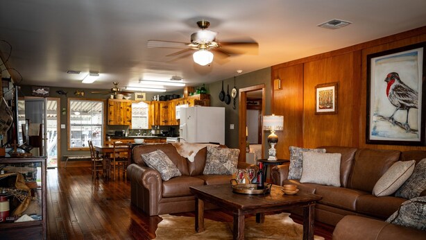 A spacious living room with a brown leather sofa, a wooden coffee table, and a cowhide rug. - Charming 2-bedroom house in fabulous Breaux Bridge with WiFi, AC (Breaux Bridge)