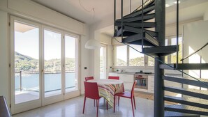 A dining area with a table and chairs, a kitchen, and a spiral staircase.