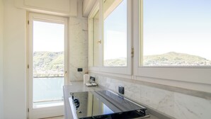 A modern kitchen with a large window, a built-in oven, and a view of a hilly landscape.