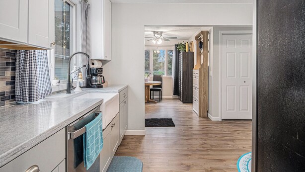 A modern kitchen with a granite countertop, a dishwasher, and a window with checkered curtains.