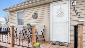 A wooden deck with a white door, a 'hello' sign, and a mailbox.