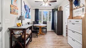 A kitchen with a dining table, chairs, a ceiling fan, and artwork on the walls.