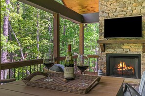 A wooden deck with a stone fireplace and a television mounted on the wall.